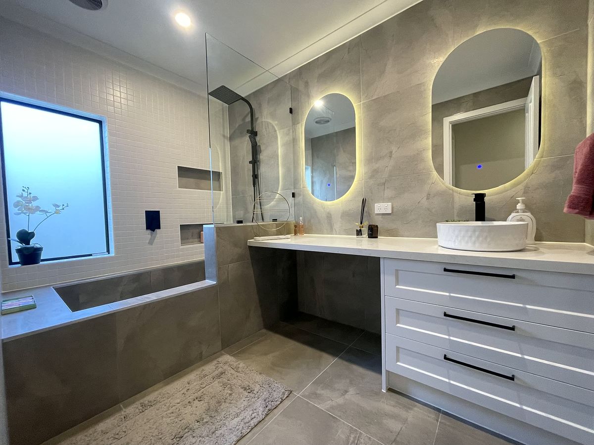 Completed bathroom with backlit mirrors and stone vanity